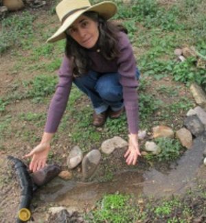 ASDM staff member Sonya Norman next to a stream of rainwater she harvested 